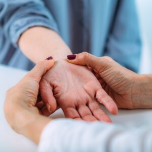 Examining the hand of a senior patient with carpal tunnel syndrome.